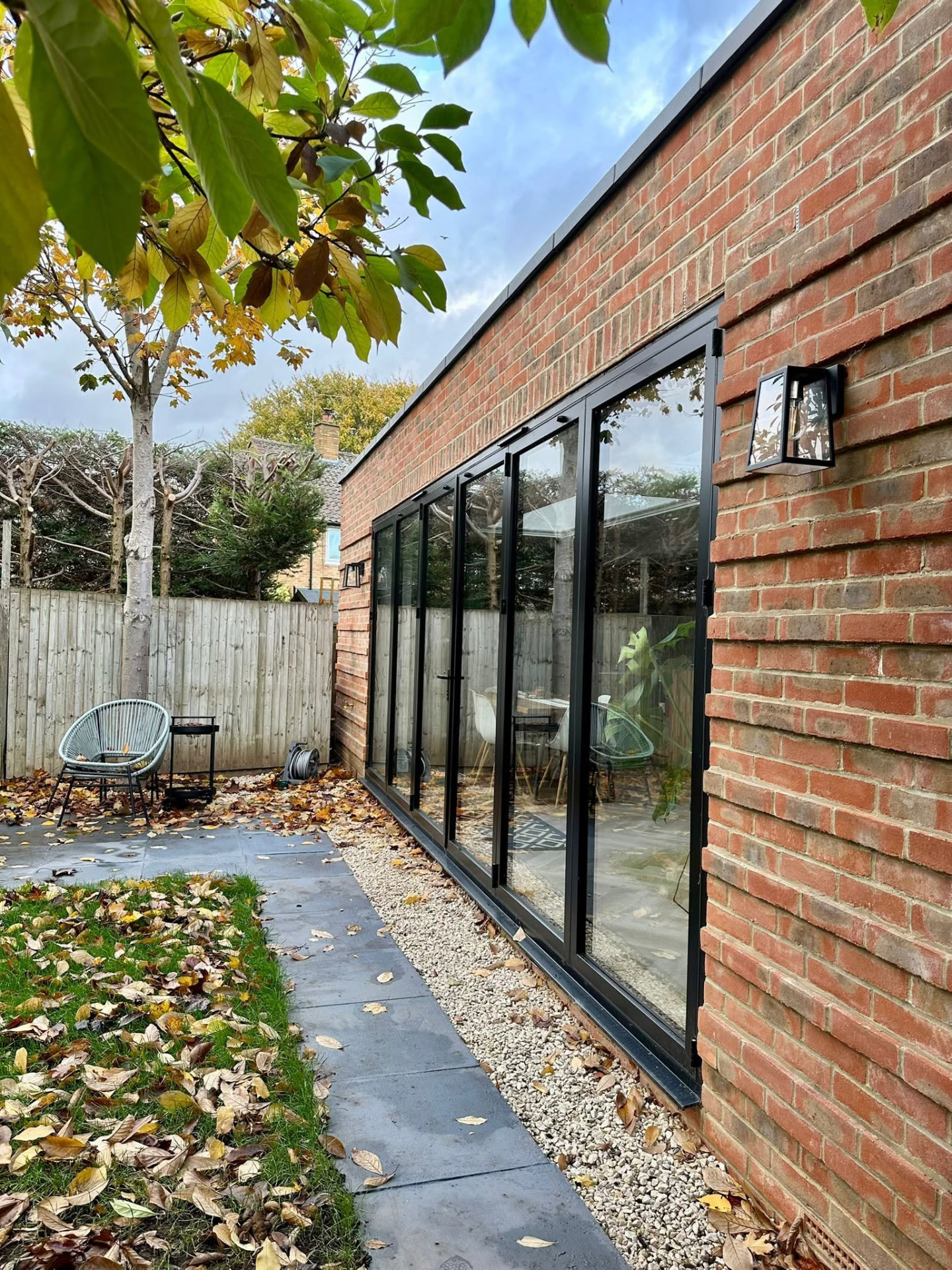 Side view of a brick extension with folding glass doors and exterior lighting