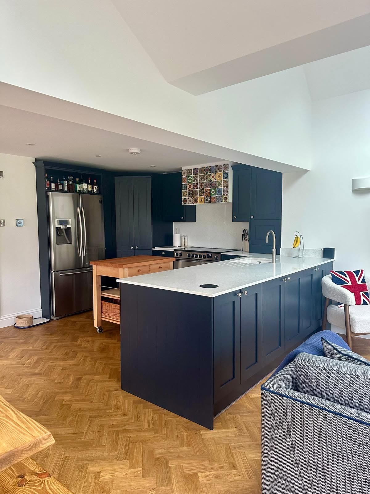 Blue shaker kitchen island with white worktops and parquet flooring in a kitchen extension