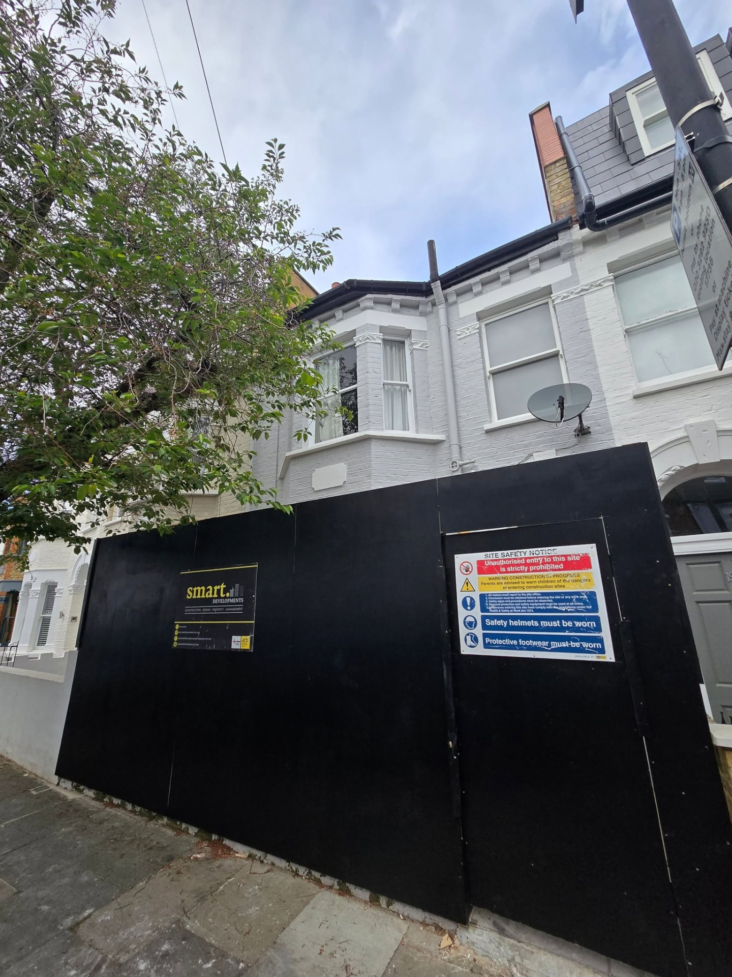 London terrace house under construction behind site hoarding and scaffolding