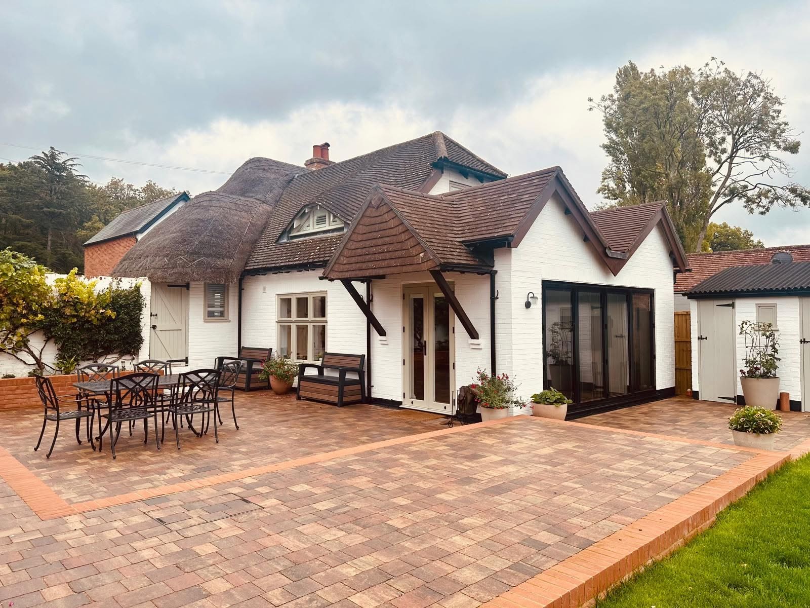 Paved patio and landscaped garden alongside an extended white rendered cottage