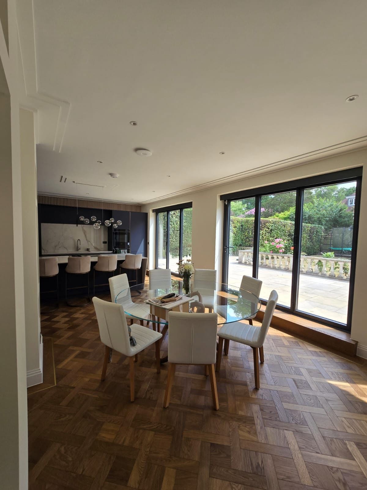 Rear extension dining room with parquet flooring and sliding glass doors to the patio