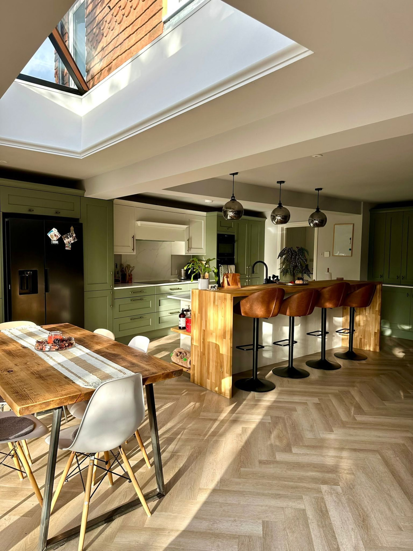 Dining table beneath a large flat rooflight in a rear kitchen extension