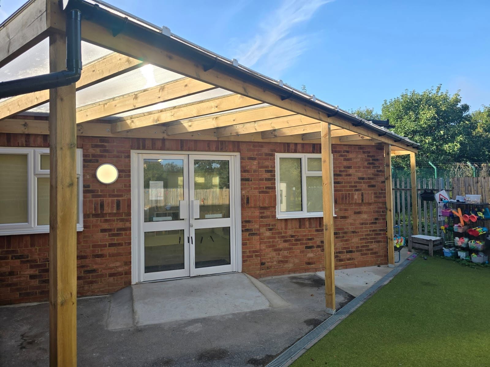 Commercial refurbishment: new oak-framed pergola with glass roof fixed to a school brick wall